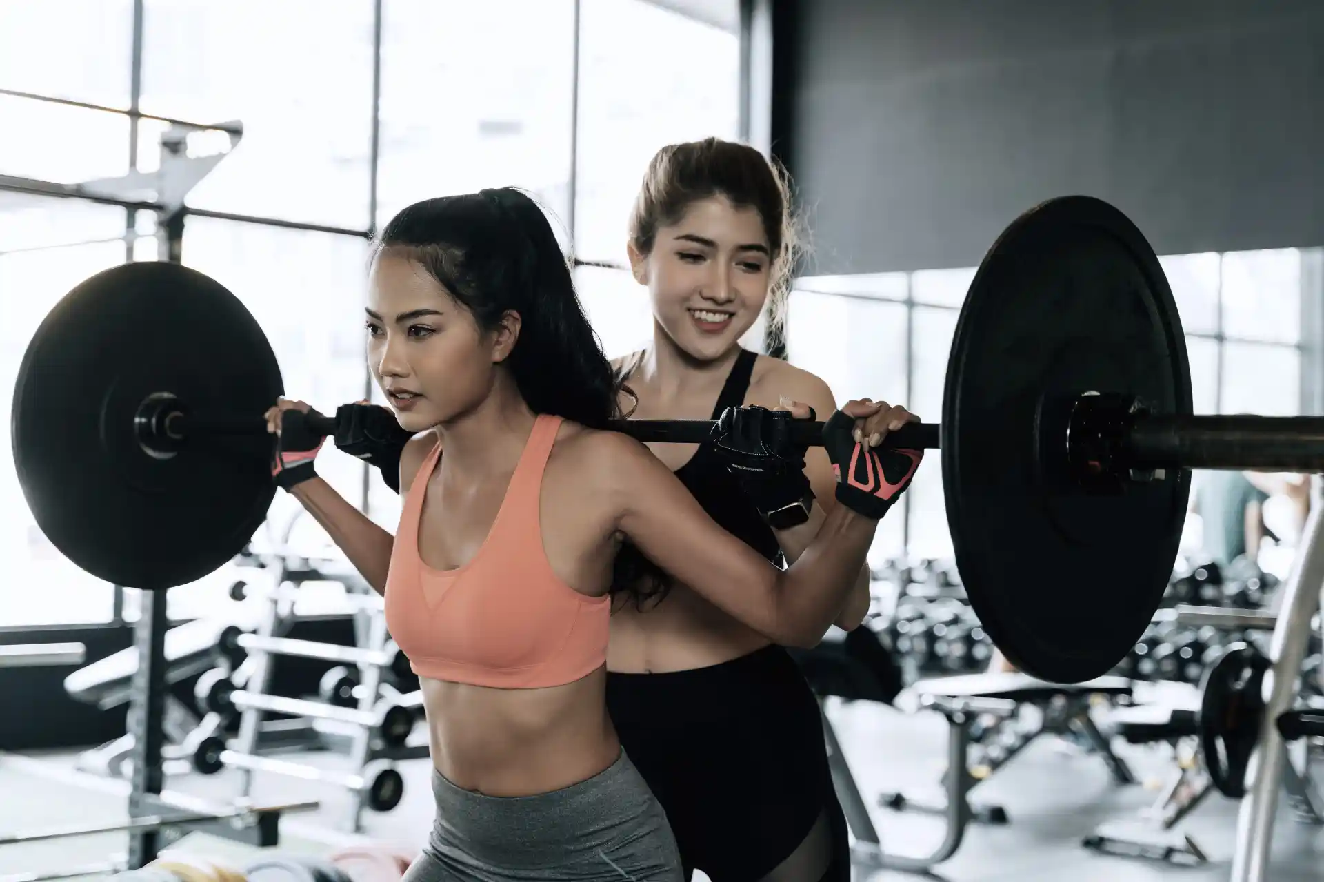 Woman training with a coach, lifting weights in a fitness studio