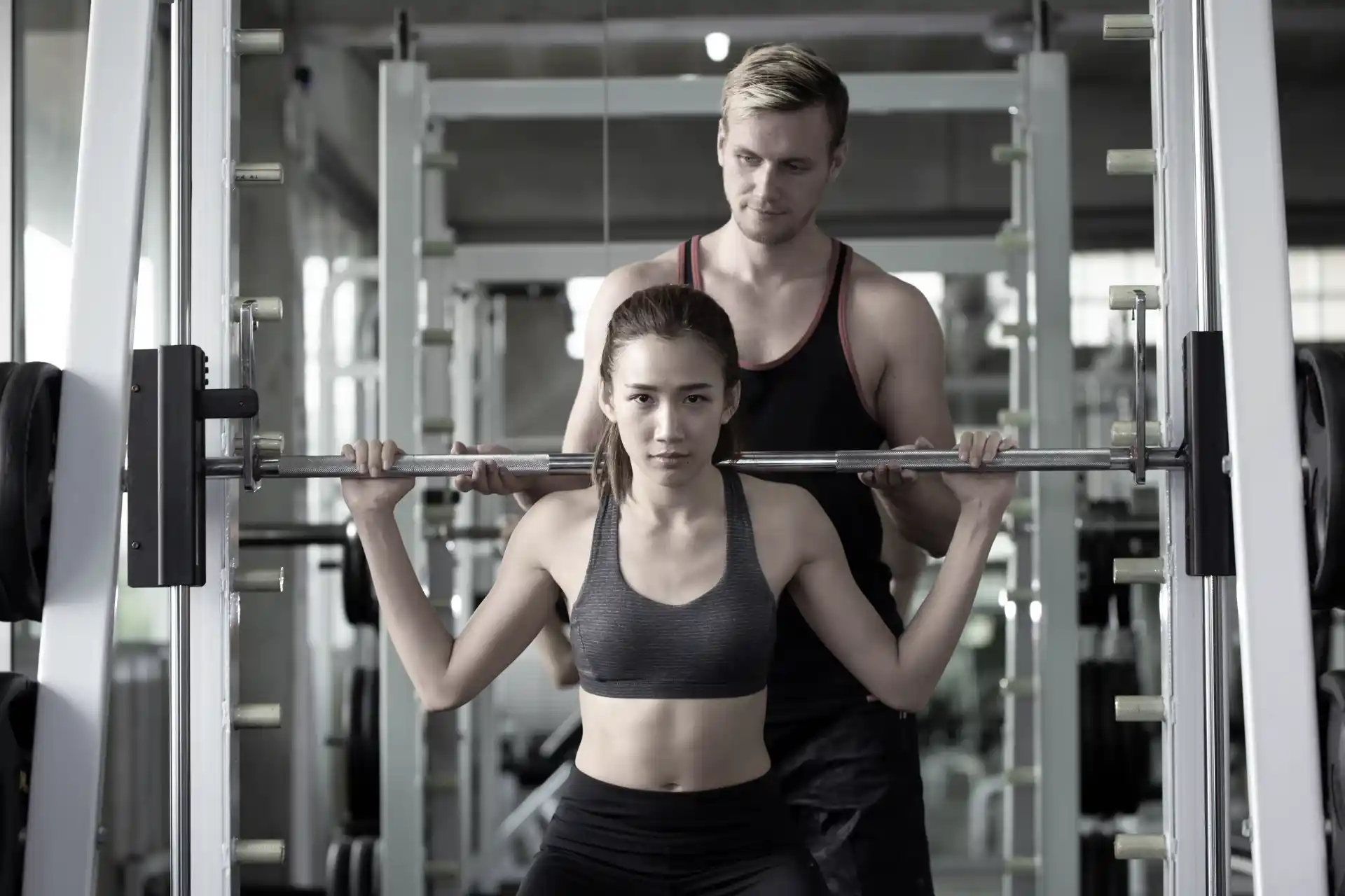 Woman lifting weights with a male coach